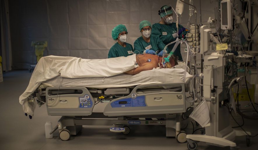 Medical personnel work in the intensive care ward for COVID-19 patients at the MontLegia CHC hospital in Liege, Belgium, Friday, Nov. 6, 2020. Coronavirus cases have surged around Europe in recent weeks, putting fresh pressure on overworked medical staff and hospitals, and forcing several countries to impose tough new movement restrictions. (AP Photo/Francisco Seco)