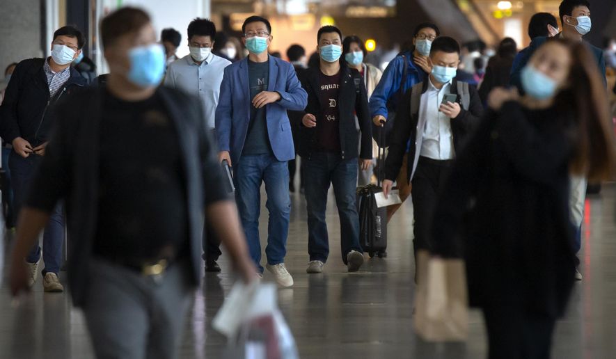 Travelers wearing face masks to protect against the coronavirus walk along a concourse at the Shanghai Hongqiao International Airport in Shanghai, Friday, Nov. 6, 2020. With the COVID-19 outbreak largely under control within its borders, air travel in China has mostly returned to pre-pandemic levels. (AP Photo/Mark Schiefelbein)
