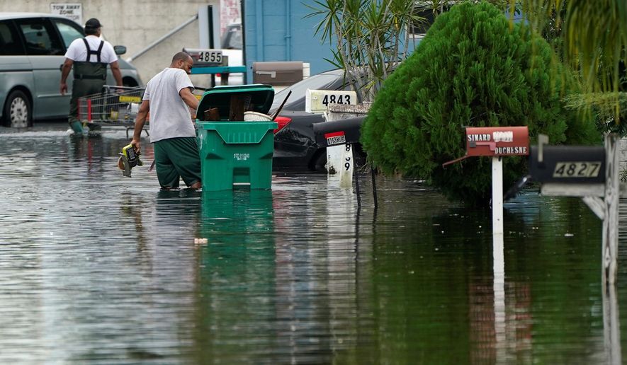 Residents clear debris from a flooded street in the aftermath of Tropical Storm Eta on Tuesday in Davie, Florida.
