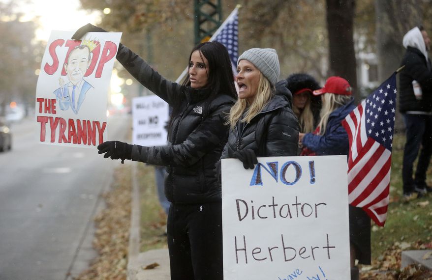 Stephanie Grant and Rebecca Olson protest Gov. Gary Herbert's mask mandate and new COVID-19 restrictions outside of the governor's mansion in Salt Lake City on Monday, Nov. 9, 2020. (Kristin Murphy/The Deseret News via AP)