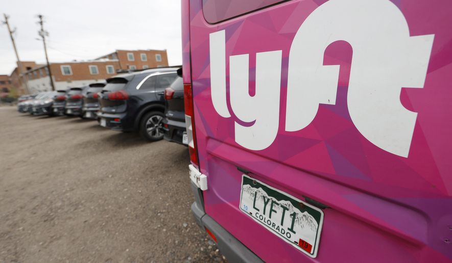 FILE - In this April 30, 2020, file photo, Kia Neros that are part of the Lyft ride-hailing fleet sit unused in a lot near Empower Field at Mile High in Denver. Lyft is still feeling the pandemic’s severe impact on the ride-hailing industry. But its third-quarter results show signs of a recovery from the previous three months when passengers stayed locked down. (AP Photo/David Zalubowski, File)