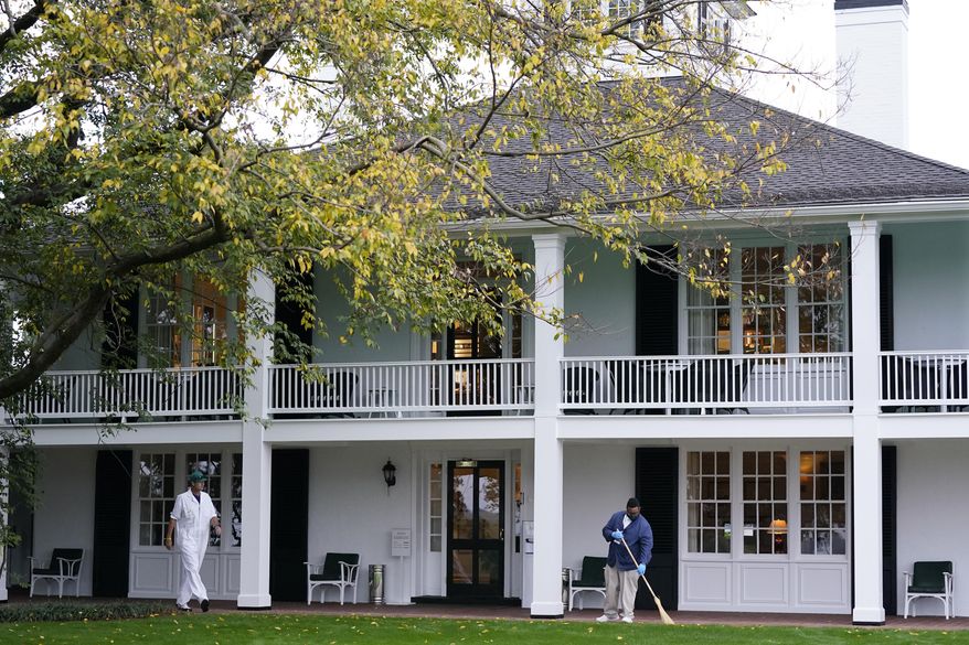 A worker sweeps leaves in front of the Augusta National Club house during a practice round for the Masters golf tournament Tuesday, Nov. 10, 2020, in Augusta, Ga. (AP Photo/David J. Phillip)