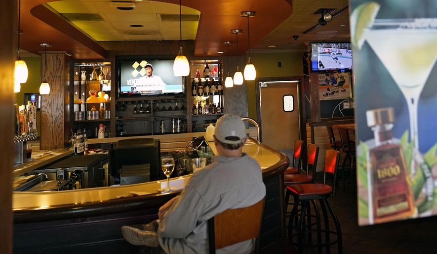 A customer sits at a bar, Tuesday, Nov. 10, 2020, at a Bloomington, Minn., restaurant. Minnesota Gov. Tim Walz announced restrictions that bars and restaurants will be required to end dine-in service between 10 p.m. and 4 a.m., beginning Friday in an effort to slow the spread of the COVID-19 virus. (AP Photo/Jim Mone)