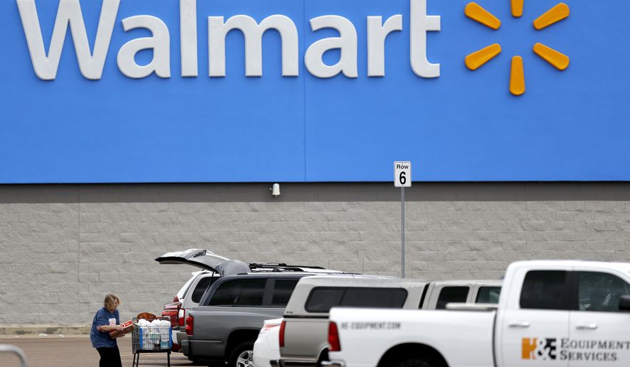 FILE - In this March 31, 2020 file photo, a woman pulls groceries from a cart to her vehicle outside of a Walmart store in Pearl, Miss. Walmart is teaming with the General Motors&#39; Cruise autonomous vehicle unit to test automated package delivery in Arizona. (AP Photo/Julio Cortez, File)