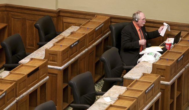 FILE - In this May 15, 2020 file photo, Rep. Roy Edwards, R-Gillette, reaches for some papers while listening to legislators speak during a special legislative session inside the Capitol in downtown Cheyenne, Wyo.  Edwards, 66, who was running unopposed for a fourth two-year term died Monday, Nov. 2, 2020, of an undisclosed illness.  (Michael Cummo/The Wyoming Tribune Eagle via AP, File)