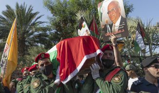 A Palestinian honor guard carries the body of Saeb Erekat into the cemetery during his funeral in the West Bank town of Jericho, Wednesday, Nov. 11, 2020. Erekat, a veteran peace negotiator and prominent international spokesman for the Palestinians for more than three decades, died on Tuesday, weeks after being infected by the coronavirus. He was 65. (AP Photo/Nasser Nasser)