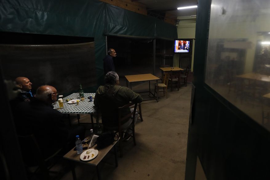 Cypriot men sit at a social club and watch the televised address of Cypriot President Nicos Anastasiades explaining the need for additional restrictions to beat back a surge in COVID-19 cases in Nicosia suburb of Lakatamia, Cyprus, on Tuesday, Nov. 11, 2020. Cyprus has put its entire southwest under a strict 19-day lockdown, banning any non-essential movement of people and shuttering bars and restaurants after a string of escalating restrictions failed to curb a sharp increase in COVID-19 infections. (AP Photo/Petros Karadjias)