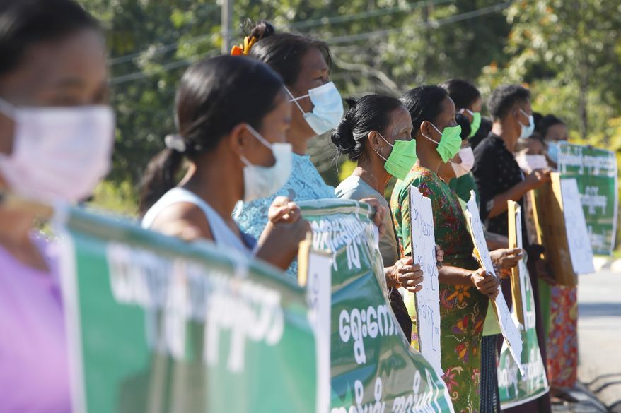 Protesters hold placards as they protest outside the Union Election Commission office, Wednesday, Nov. 11, 2020, in Naypyitaw, Myanmar. The military backed main opposition party on Wednesday said it does not recognize last Sunday's Myanmar election, citing unfairness, and rejected the results. (AP Photo/Aung Shine Oo)