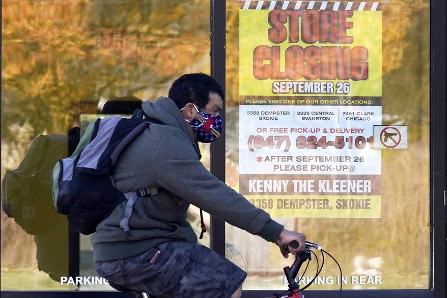 FILE - In this Friday, Nov. 6, 2020 file photo, a man wearing a face mask rides a bicycle past a closed store in Wilmette, Ill. The state set another single-day record for coronavirus infections Tuesday, Nov. 10, 2020, pushing the total number of people who have tested positive for the virus in the state since the pandemic began past 500,000. (AP Photo/Nam Y. Huh)