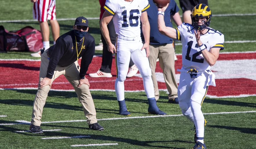 Michigan head coach Jim Harbaugh, left, watches as quarterback Cade McNamara (12) warms up before an NCAA college football game against Indiana, Saturday, Nov. 7, 2020, in Bloomington, Ind. (AP Photo/Doug McSchooler)