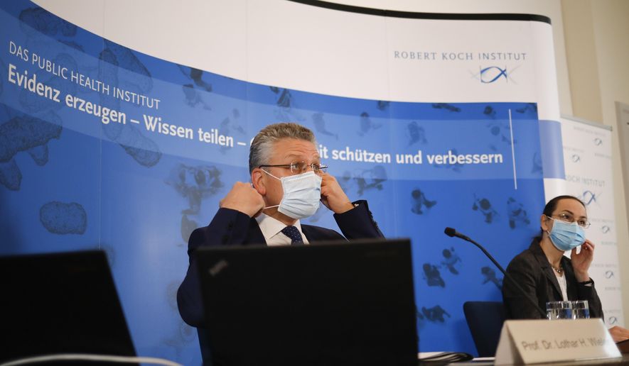 The head of the Robert Koch Institute, German national agency and research institute, responsible for disease control and prevention, Lothar Wieler, left, and Ute Rexroth, a senior RKI official arrive for a news conference on the coronavirus and the COVID-19 disease situation in Germany in Berlin, Thursday, Nov. 12, 2020. Slogan in background reads: &#39; Generating evidence sharing knowledge protecting and improving health&#39;. (AP Photo/Markus Schreiber, Pool)