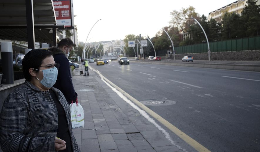 People wearing masks to help protect against the spread of coronavirus, wait at a bus station, in Ankara, Turkey, Wednesday, Nov. 11, 2020. Turkey&#39;s government had urged the residents of big cities to limit their mobility and called on employers to offer workers flexible or staggered working hours and the possibility of working from homes.(AP Photo/Burhan Ozbilici)