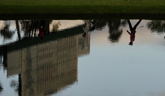 Dylan Frittelli, of South Africa, is reflected in the water has he walks along the 16th fairway during the first round of the Masters golf tournament Thursday, Nov. 12, 2020, in Augusta, Ga. (AP Photo/Matt Slocum)