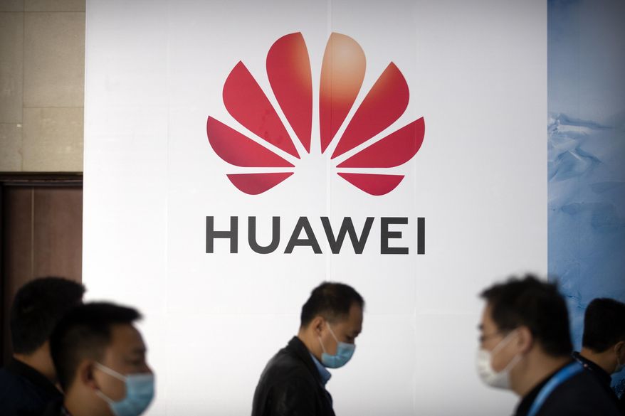 People walk past a billboard advertising Chinese tech company Huawei at the PT Expo in Beijing on Oct. 14, 2020. U.S. President Donald Trump has stepped up a conflict with China over security and technology by issuing an order barring Americans from investing in companies that U.S. officials say are owned or controlled by the Chinese military. (AP Photo/Mark Schiefelbein)