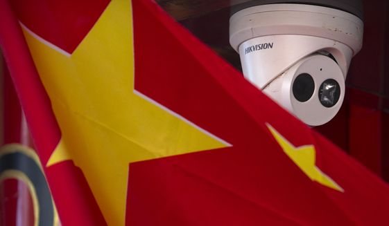 A Chinese flag hangs near a Hikvision security camera outside of a shop in Beijing on Oct. 8, 2019. (AP Photo/Mark Schiefelbein) ** FILE **