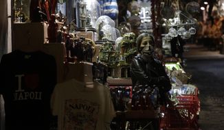 A woman stands outside her nativity scenes shop along San Gregorio Armeno street in Naples, in the Campania region, Italy, Friday, Nov. 13, 2020. The regions of Campania and Tuscany were designated red zone on Friday, signaling the dire condition of a hospitals struggling with a surge of new admissions. (AP Photo/Gregorio Borgia)