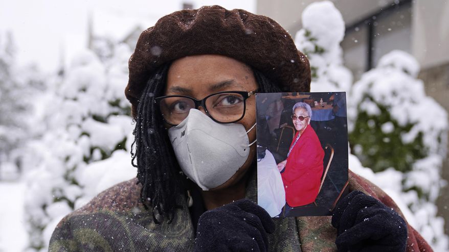 Priscilla Flint-Banks holds a photograph of her 87-year-old mother, Ruby Mae Kinney, who died during April of COVID-19, Friday, Oct. 30, 2020, in the Dorchester neighborhood of Boston. Once a coronavirus hot spot, Massachusetts was seen as a model for infection control this summer as coronavirus cases and deaths dwindled. Now, experts are warning the state could be headed for a bleak winter as its cases climb once again and confirmed deaths surpass 10,000. Massachusetts hit 10,015 confirmed coronavirus deaths on Thursday, Nov. 12, 2020 nearly nine months after the state’s initial case was detected. (AP Photo/Charles Krupa)