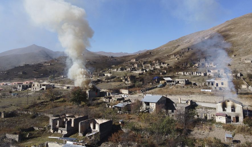 In this photo taken with a drone, smoke rises from burning houses as people leave the separatist region of Nagorno-Karabakh to Armenia,  Saturday, Nov. 14, 2020. The territory is to be turned over to Azerbaijan on Sunday as part of territorial concessions in an agreement to end six weeks of intense fighting with Armenian forces. Hundreds of thousands of Azeris were displaced by the war that ended in 1994. It is unclear when any civilians might try to settle in Karvachar — which will now be known by its Azeri name Kalbajar — or elsewhere. (AP Photo/Dmitry Lovetsky)