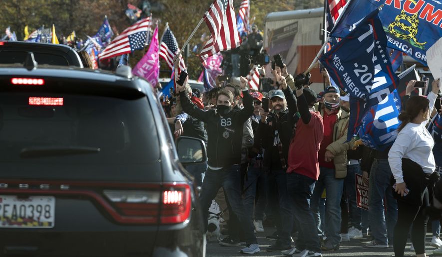 President Donald Trump drives by a group of supporters participating in a rally near the White House, Saturday, Nov. 14, 2020, in Washington. (AP Photo/Evan Vucci)