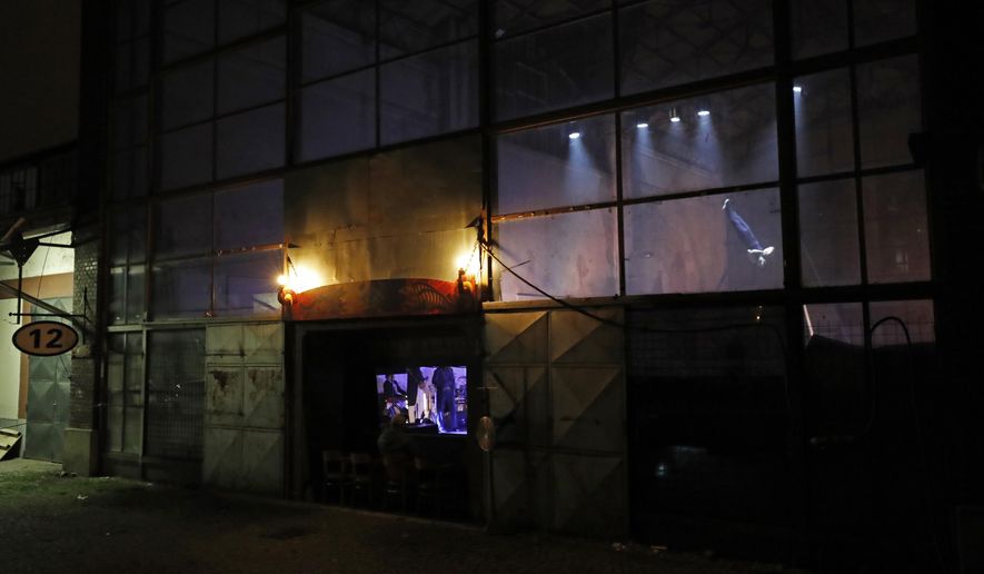 Spectators enjoy a performance through a window at a theater in Prague, Czech Republic, Tuesday, Nov. 10, 2020. Desperate to play for at least some spectators amid the coronavirus pandemic, a new circus company Cirk La Putyka has started to play five-minutes performances on a stage behind a window. With all theaters closed due to the government restrictive measures, the theater adopted the same principle as the restaurants closed for the same reason. (AP Photo/Petr David Josek)