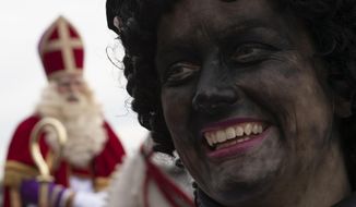 -FILE- In this Saturday Nov. 16, 2019, file image, Zwarte Piet, or Black Pete, right, the controversial blackfaced sidekick of Saint Nicholas, rear left, walks in a parade in Scheveningen harbor, near The Hague, Netherlands. Saint Nicholas, the gift-bearing patron saint of children, was arriving in the Netherlands on Saturday amid a partial coronavirus lockdown that forced the cancelation of celebrations in many towns and cities. (AP Photo/Peter Dejong, File)