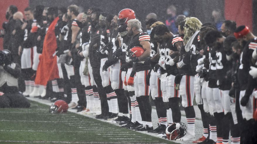 Members of the Cleveland Browns stand for the National Anthem during a downpour of rain and hail before an NFL football game against the Houston Texans, Sunday, Nov. 15, 2020, in Cleveland. The game was delayed due to lighting. (AP Photo/David Richard)