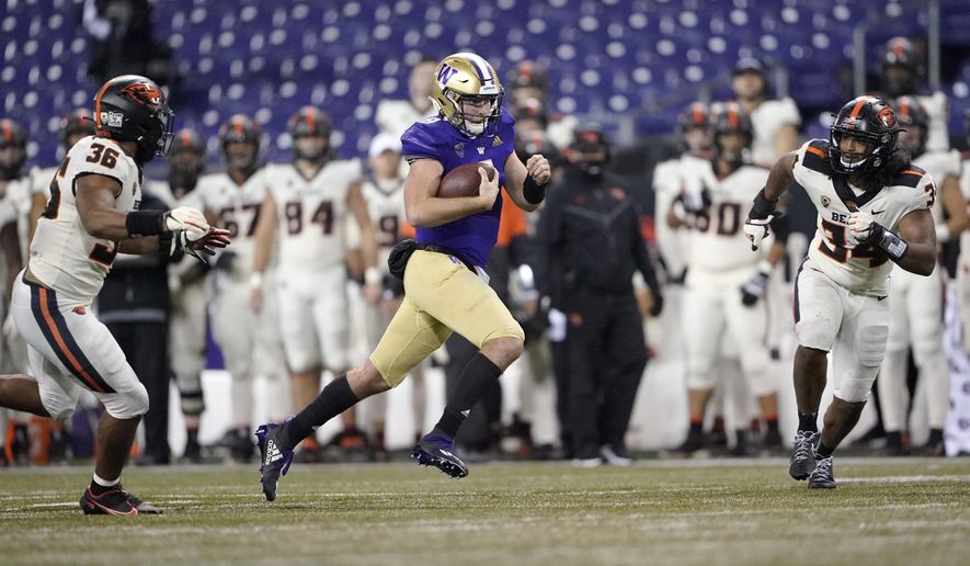 Washington quarterback Dylan Morris keeps the ball as Oregon State's Omar Speights, left, and Avery Roberts, right, close in during the second half of an NCAA college football game, Saturday, Nov. 14, 2020, in Seattle. Washington won 27-21. (AP Photo/Ted S. Warren)