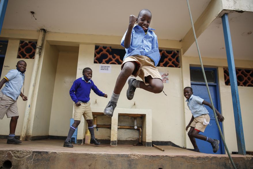 FILE - In this Monday, Oct. 12, 2020 file photo, schoolchildren joke around and play at the Olympic Primary School in Kibera, one of the capital Nairobi's poorest areas, as schools partially re-opened to allow those students due for examinations which had been postponed to prepare, in Kenya. As schools reopen in some African countries after months of lockdown, relief is matched by anxiety over everything from how to raise tuition fees amid the financial strain wrought by the COVID-19 pandemic to how to protect students in crowded classrooms. (AP Photo/Brian Inganga, File)