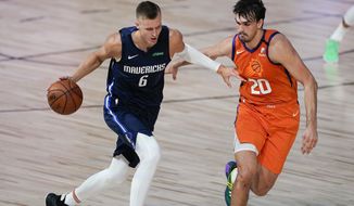 Dallas Mavericks forward Kristaps Porzingis (6) drives against Phoenix Suns forward Dario Saric (20) during the first half of an NBA basketball game Sunday, Aug. 2, 2020, in Lake Buena Vista, Fla. Porzingis will miss the start of the season as the Mavericks star continues recovery from surgery to repair a torn meniscus in his right knee. Director of basketball operations Donnie Nelson said in a radio interview Monday, Nov. 16, 2020, the club was being cautious with Luka Doncic&#39;s European sidekick, who missed more than a season because of another knee injury.(AP Photo/Ashley Landis, Pool)