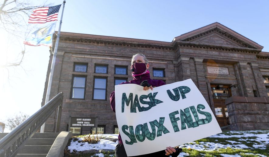 Jenae Ruesink holds a sign demanding a mask mandate from city council on Monday, Nov. 16, 2020 outside Carnegie Town Hall in Sioux Falls, S.D. (Erin Bormett/The Argus Leader via AP)