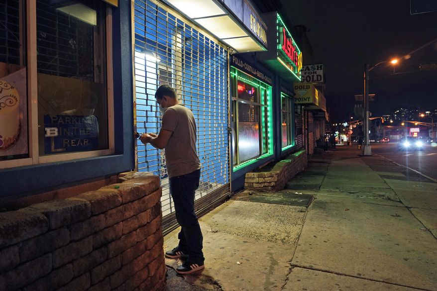 FILE - In this Nov. 12, 2020, file photo, on a mostly empty street, an employee of Justin's BBQ closes up for the night in Newark, N.J. An increasing number of governors and mayors are imposing restrictions ahead of Thanksgiving for fear that holiday travel and family gatherings will only worsen the record-breaking, coast-to-coast resurgence of the coronavirus. (AP Photo/Seth Wenig, File)