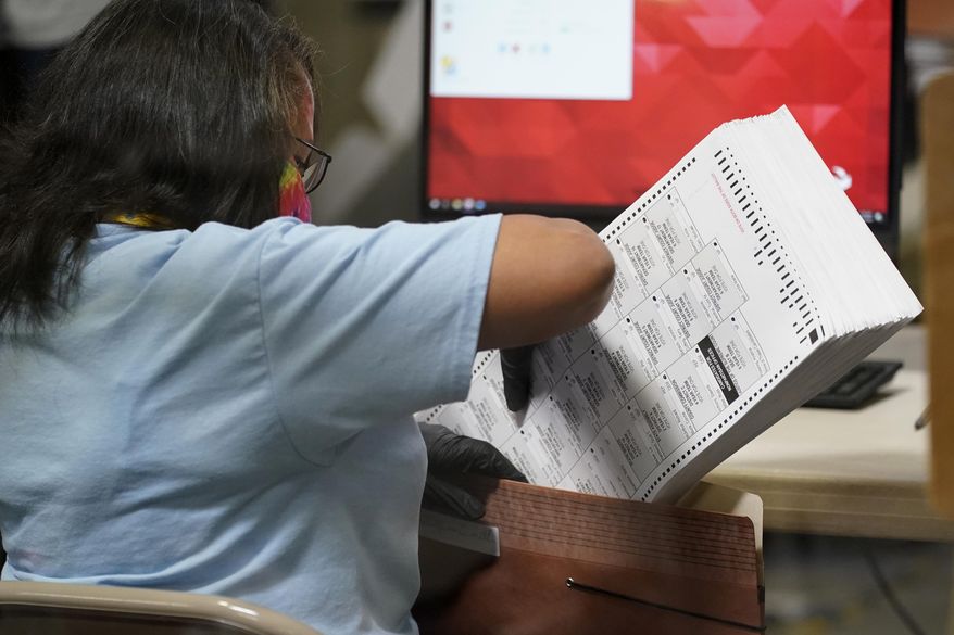In this Nov. 5, 2020, file photo a county election worker scans mail-in ballots at a tabulating area at the Clark County Election Department, Thursday, Nov. 5, 2020, in Las Vegas. Election-related lawsuits flew Tuesday, Nov. 17, 2020, in Nevada, where a voting watchdog group organized by a conservative Nevada activist is asking a judge to nullify the Nov. 3 statewide election. (AP Photo/John Locher, File)