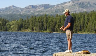 FILE - In this July 7, 2004, file photo, Dennis Rogers, of Corona, Calif., fishes off a dock at Ponderosa Park in McCall, Idaho, while vacationing. A private investment firm&#39;s proposal to swap private timberland in northern Idaho for up to 28,000 acres of public state land in and around the tourist destination of McCall that is also a popular area for vacation homes is facing opposition from local governments, environmental groups and private citizens. Trident Holdings LLC pitched the plan Tuesday, Nov. 17, 2020, to Republican Gov. Brad Little and four other statewide-elected members of the Idaho Land Board. (AP Photo/Matt Cilley, File)