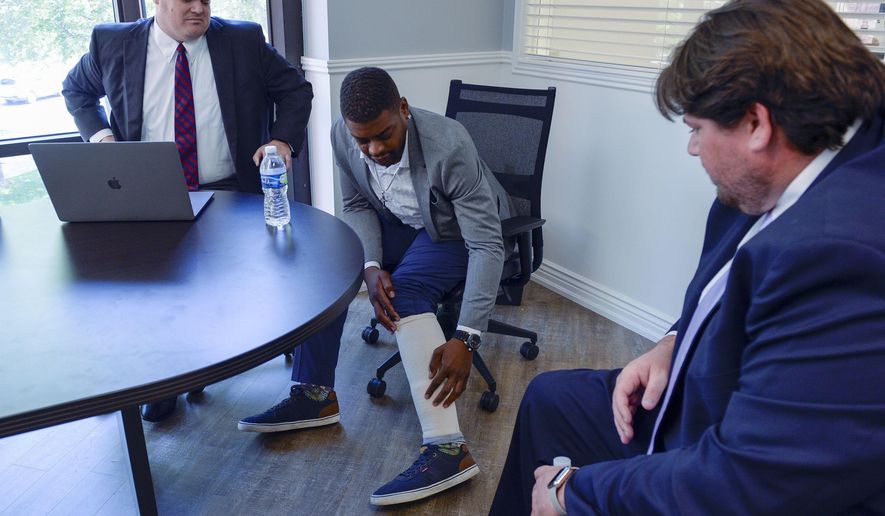 FILE - Jeffery Ryans points at his ankle as he discusses his encounter with Salt Lake City police at his attorney's office on Aug. 5, 2020, in Salt Lake City. Salt Lake City's police dog apprehension program will remain suspended indefinitely, the police chief announced, after an officer ordered a dog to attack Ryans, who had put his hands in the air. Weeks after body camera footage of an officer directing a dog to attack Ryans came to light, the department ordered an internal affairs audit of its K9 apprehension program, Chief Mike Brown told reporters Friday, Sept. 25, 2020. (Leah Hogsten/The Salt Lake Tribune via AP, File)
