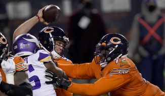 Chicago Bears quarterback Nick Foles tries to throw under pressure from Minnesota Vikings defensive end Ifeadi Odenigbo, left, as Bears offensive tackle Charles Leno Jr., right, pushes Odenigbo during the second half of an NFL football game Monday, Nov. 16, 2020, in Chicago. Foles was injured on the play and left the game. (AP Photo/Charles Rex Arbogast) **FILE**