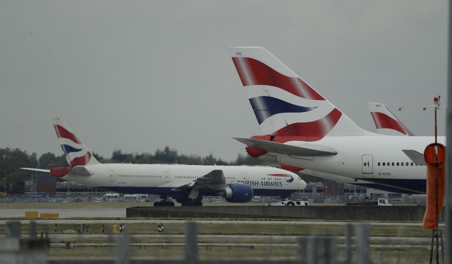FILE - In this Monday, Sept. 9, 2019 file photo, a British Airways plane, at left, is towed past other planes sitting parked at Heathrow Airport in London. British Airways said Tuesday Nov. 17, 2020, that it will start testing passengers flying from the U.S. to London’s Heathrow Airport for COVID-19 in an effort to persuade the British government it should scrap rules requiring most international travelers to quarantine for 14 days. (AP Photo/Matt Dunham, File)