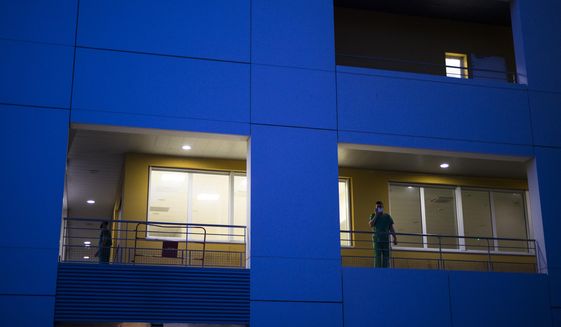 A hospital worker takes a break on an outdoor walkway as the day shift comes to an end and night falls upon the La Timone hospital in Marseille, southern France, Thursday, Nov. 12, 2020. France is more than two weeks into its second coronavirus lockdown, and intensive care wards have been over 95% capacity for more than 10 days now. Associated Press journalists spent 24 hours with the intensive care team at La Timone, southern France&#x27;s largest hospital, as they struggled to keep even one bed open for the influx of patients to come. (AP Photo/Daniel Cole)