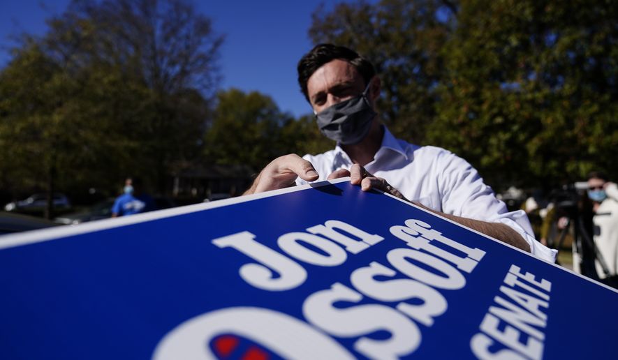 Georgia Democratic candidate for U.S. Senate Jon Ossoff grabs signs to give out during a drive-through yard sign pick-up event on Wednesday, Nov. 18, 2020, in Marietta, Ga. Ossoff and Republican candidate for Senate Sen. David Perdue are in a runoff election for the Senate seat. (AP Photo/Brynn Anderson)