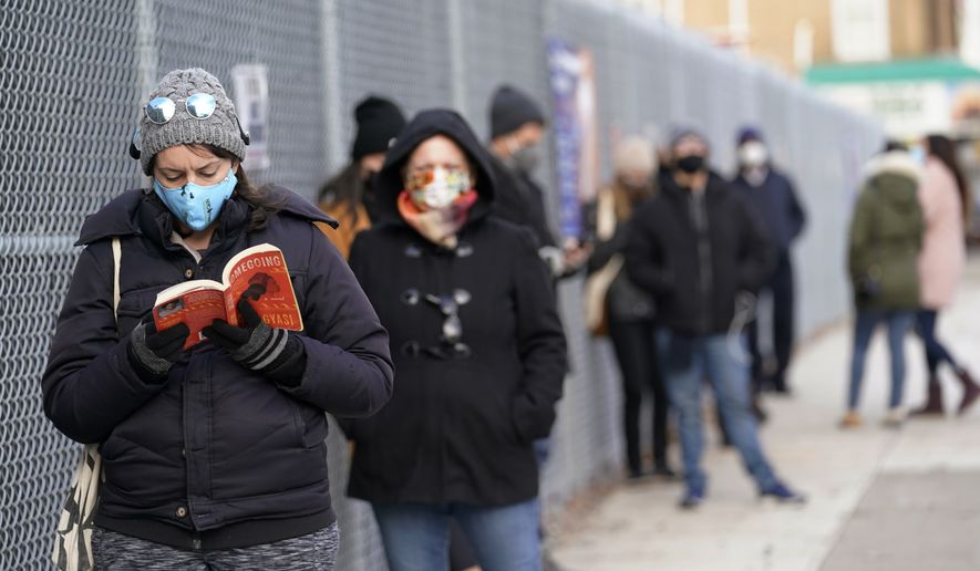 Ashley Gannon, left, reads a book as she and others wait in line outside a New York City Health + Hospitals COVID testing site in the Brooklyn borough of New York, Thursday, Nov. 19, 2020. Gannon says she gets tested periodically to make sure she is coronavirus-free. Some said they waited more than two hours to get a rapid test, one of two kinds of tests available at this particular site. Workers at the site said rapid test results take one to two days, while a regular test could take two to four days. At this testing site, there were longer lines for the rapid test as they are not available at all sites. (AP Photo/Kathy Willens)