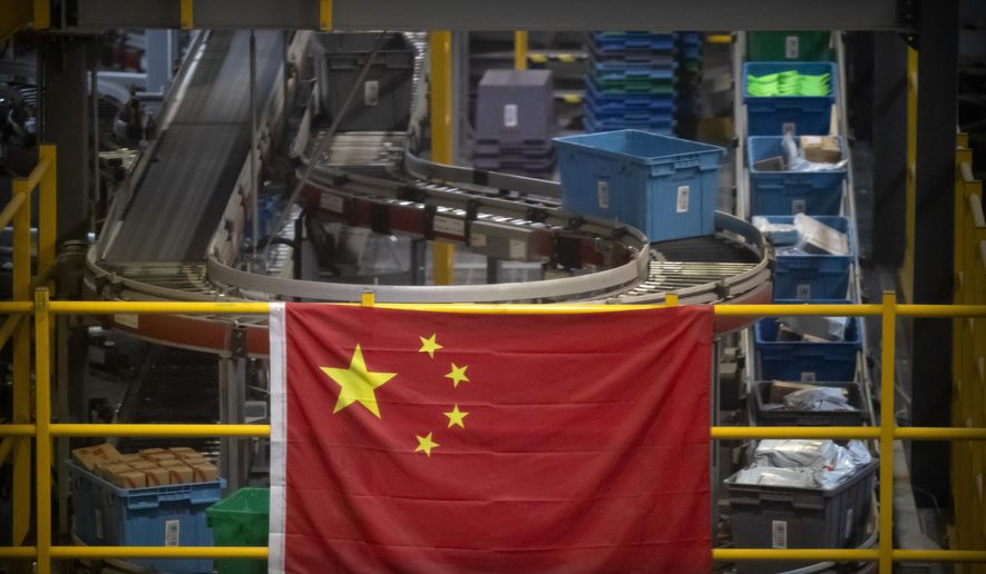 In this Nov. 11, 2020, file photo a Chinese flag hangs near an automated parcel handling line at a warehouse for an online retailer in Beijing. President Donald Trump has identified China as the country’s biggest foe and the Justice Department mirrored that emphasis over the last four years with a drumbeat of cases against defendants ranging from hackers accused of targeting intellectual property to professors charged with grant fraud. (AP Photo/Mark Schiefelbein, File)