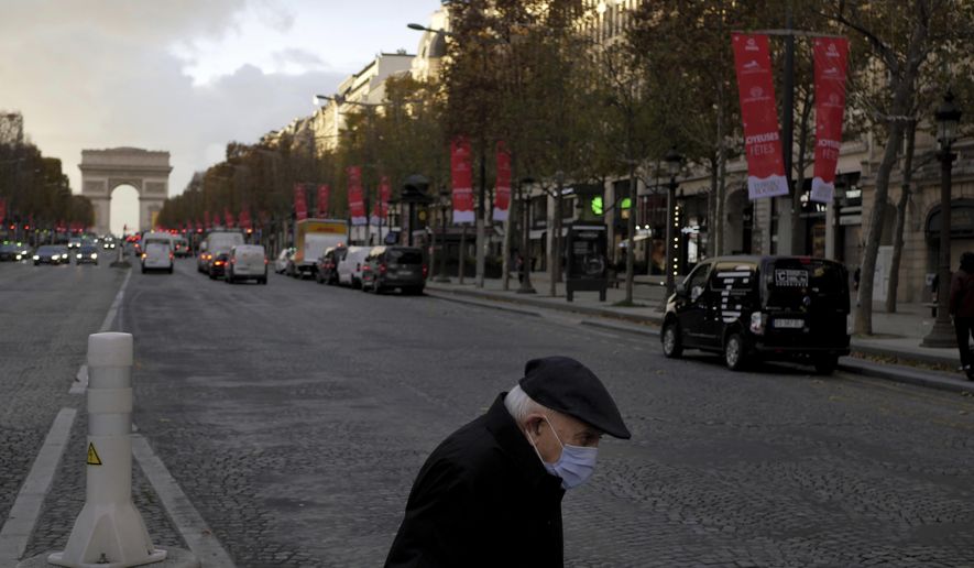 An elderly man wears a face mask as he walks on the Champs Elysee avenue, in Paris, Thursday, Nov. 19, 2020. France has surpassed 2 million confirmed cases of coronavirus, the fourth-highest total in the world. (AP Photo/Thibault Camus)