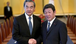 FILE - In this Nov. 25, 2019, file photo, Chinese Foreign Minister Wang Yi, left, poses with his Japanese counterpart Toshimitsu Motegi for a photo prior to a meeting in Tokyo. Motegi announced Friday, Nov. 20, 2020 that his Chinese counterpart Wang will visit Tokyo next week as the two Asian powers discuss ways to resume bilateral visits to revive their pandemic-hit economies and other regional issues. (Behrouz Mehri/Pool Photo via AP)