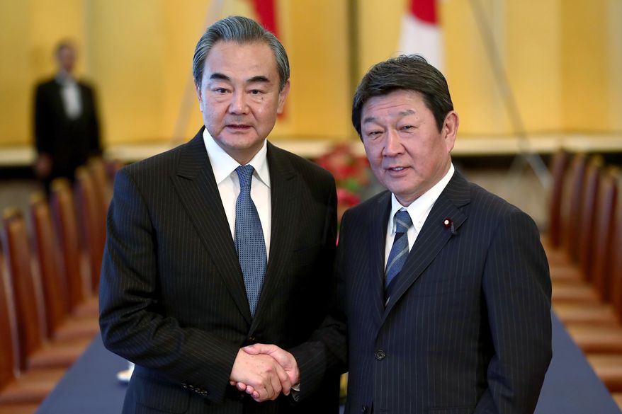 FILE - In this Nov. 25, 2019, file photo, Chinese Foreign Minister Wang Yi, left, poses with his Japanese counterpart Toshimitsu Motegi for a photo prior to a meeting in Tokyo. Motegi announced Friday, Nov. 20, 2020 that his Chinese counterpart Wang will visit Tokyo next week as the two Asian powers discuss ways to resume bilateral visits to revive their pandemic-hit economies and other regional issues. (Behrouz Mehri/Pool Photo via AP)