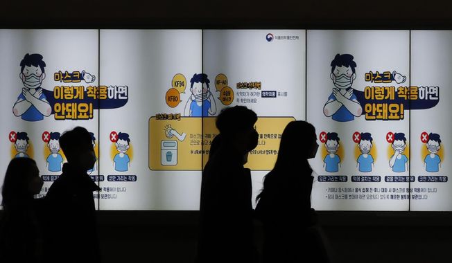 People wearing face masks walk past a screen showing the precautions against the coronavirus in Seoul, South Korea, Friday, Nov. 20, 2020. The screen reads: &amp;quot;Don&#x27;t wear such masks like below images.&amp;quot; (AP Photo/Lee Jin-man)