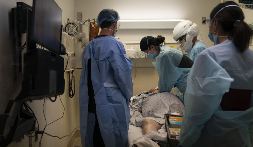 FILE - In this Nov. 19, 2020, file photo, EMT Giselle Dorgalli, third from right, performs chest compression on a patient who tested positive for coronavirus in the emergency room at Providence Holy Cross Medical Center in the Mission Hills section of Los Angeles. (AP Photo/Jae C. Hong, File)