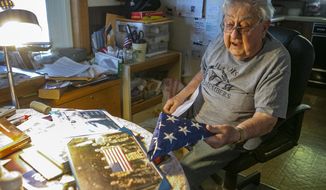 Robert Teichgraeber, 100, talks about the many gifts and honors he has received for his service in World War II on Nov. 6, 2020 in Collinsville, Ill.. He holds a flag flown in his honor in combat over Afghanistan aboard a United States Air Force C-130J assigned to the 61st Expeditionary Airlift Squadron in July of 2000. He survived 421 days as a prisoner after his plane was shot down during a bombing run in WWII. (Derik Holtmann/Belleville News-Democrat via AP)