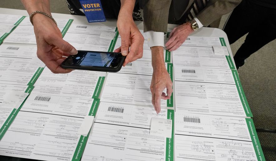 In this Nov. 6, 2020, photo, a canvas observer photographs Lehigh County provisional ballots as vote counting in the general election continues in Allentown, Pa. (AP Photo/Mary Altaffer, File)