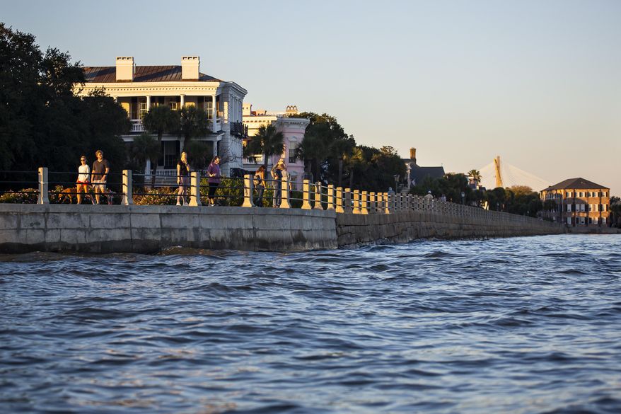 As high tide laps against the sea wall tourist walk down the Battery in Charleston, S.C. Friday, Nov. 13, 2020. Charleston has remained relatively unscathed this hurricane season. That means more time to mull a $1.75 billion proposal by the Army Corps of Engineers that features a sea wall along the city's peninsula to protect it from deadly storm surge during hurricanes. (AP Photo/Mic Smith)