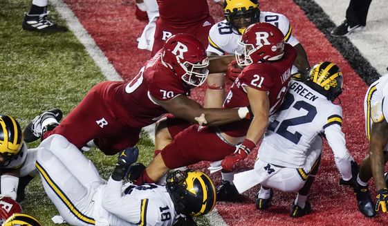 Rutgers&#39; Johnny Langan (21) rushes against Michigan&#39;s Luiji Vilain (18) and Gemon Green (22) for a touchdown during the first half of an NCAA college football game Saturday, Nov. 21, 2020, in Piscataway, N.J. (AP Photo/Frank Franklin II)