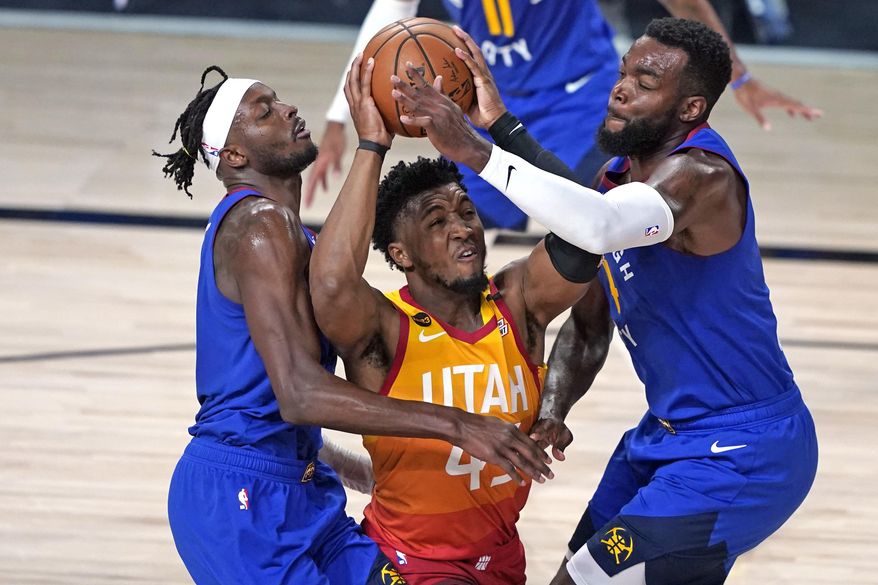 FILE - In this Aug. 30, 2020, file photo, Utah Jazz&#39;s Donovan Mitchell, center, goes up to shoot as Denver Nuggets&#39; Jerami Grant, left, and Paul Millsap, right, defend during the second half of an NBA basketball first round playoff game in Lake Buena Vista, Fla. Mitchell agreed Sunday, Nov. 22, 2020, to a five-year, $163 million extension to remain with the Jazz. (AP Photo/Ashley Landis, File)